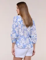 Blusa holgada de gasa estampada en tonos amarillos y azules, con cuello en V, mangas 3/4 abullonadas y alforzas horizontales.