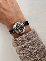 Pulsera con dije plateado con la imagen del Espíritu Santo y cinta de terciopelo elástica color verde petróleo.