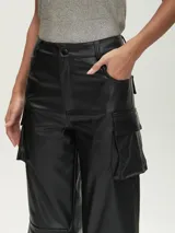 Pantalón negro de cuero sintético, corte ancho, con bolsillos cargo y tiro alto.