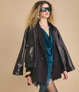 Blazer de sastrería en color negro, de corte alargado y estructura recta. Presenta solapas clásicas, cierre frontal con dos botones, hombros estructurados y mangas largas con detalle de botones en los puños. Incluye bolsillos decorativos y forro interno.