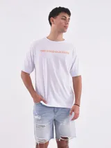 Remera blanca de corte holgado con la frase "The Good Old Days" estampada en color naranja.