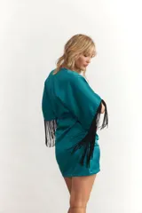 Vestido corto celeste de satén con escote en V, mangas cortas con flecos negros y drapeado en la falda.