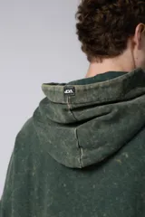 Buzo canguro de corte oversize en color verde con efecto de teñido desgastado. Cuenta con capucha, bolsillo frontal tipo canguro y puños acanalados.
