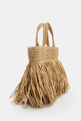 Bolso de mano de efecto trenzado color beige, con detalle de flecos en el cuerpo, doble asa de mano y cierre mediante clip metálico.