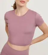 Remera deportiva tipo crop top de color negro, con cuello redondo y mangas cortas. Confeccionada en tejido de malla suave y elástico.