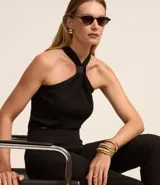 Pantalón de sastrería corte carrot, color beige, con cintura alta, pinzas frontales y cinturón fino incorporado con hebilla metálica.