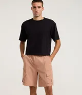 Bermuda cargo baggy negra, confeccionada en poliéster con cintura elástica, cordón ajustable y bolsillos laterales con cierre de cremallera.