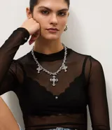 Conjunto femenino compuesto por un collar corto de cadena con dijes de cruz decorados y caravanas a juego.