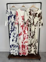 Vestido largo color crudo con estampado floral marrón, escote en V cruzado, mangas tres cuartos con volados y falda con niveles fruncidos.