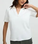 Polo de manga corta color marrón, con cuello abierto y tejido de suedine de algodón BCI.