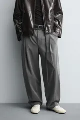 Pantalón de corte balloon fit en color gris, confeccionado en tejido con viscosa. Presenta pliegues frontales, cintura con cinturón integrado a contraste, bolsillos laterales y bolsillos traseros de vivo.