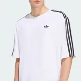 Remera oversized Adidas Adicolor de color blanco, de corte holgado, con cuello redondo, mangas cortas con las icónicas tres tiras negras y el logo Trefoil bordado en el pecho.
