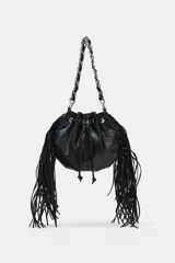 Bolso tipo saca color negro, de formato mini, con flecos laterales, cierre fruncido con cordones y correa combinada de cadena y tira de cuero sintético.