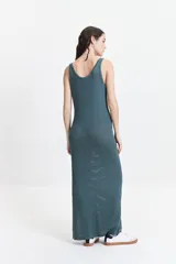 Vestido largo de punto con textura acanalada, escote redondo y tirantes anchos. Presenta una silueta ajustada al cuerpo y un tajo lateral en la parte inferior.