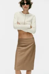 Falda midi de tiro medio confeccionada en tejido efecto piel de color marrón, con costura central frontal y cierre lateral con cremallera oculta.