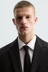 Blazer slim fit de color negro, confeccionada en tejido con viscosa. Presenta cuello con solapas de muesca, cierre frontal con botones, bolsillo de vivo en el pecho y bolsillos de solapa en la cadera.