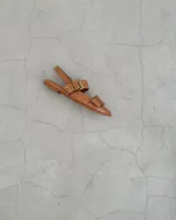 Sandalias bajas de cuero color marrón claro con tiras finas y hebillas doradas.