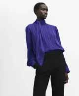 Blusa de poliéster color azul, con cuello alto, lazada integrada, cierre lateral con botones y mangas largas abullonadas con puños ajustados.
