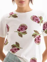 Remera blanca de manga corta y cuello redondo, con estampado de peras en tonos rosados y verdes.