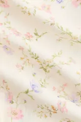 Blusa en tejido liviano de mezcla de lino, de color blanco con estampado floreado. Cuenta con cuello redondo, cierre frontal de botones y mangas globo tres cuartos con puños elásticos.
