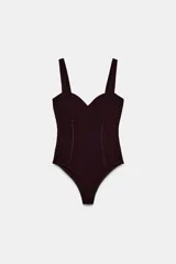 Body de escote corazón y tirantes anchos, con costuras frontales tipo corset y cierre inferior con botones a presión.