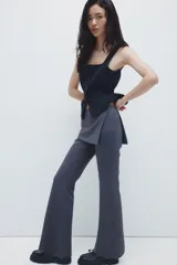 Pantalón acampanado de tiro alto con pollera mini integrada en la cintura, confeccionado en tela lisa de color gris oscuro.