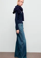 Pantalón de jean estilo wide leg con tiro medio, cierre frontal de cremallera y botón, cinco bolsillos y detalle de tachuelas en la cintura.