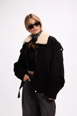 Campera de gamuza color marrón con cuello de corderito sintético en color crema. Presenta un diseño oversize con cierre frontal, solapas con broches metálicos y una tira ajustable en el ruedo.