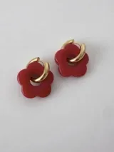 Aros de acero quirúrgico dorados con dije en forma de flor color rojo.