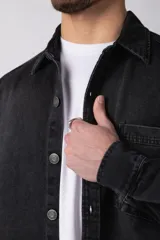Chaqueta de jean negro desgastado, de corte recto, con cuello clásico, cierre frontal con botones y bolsillo en el pecho. Confeccionada en denim de algodón de 12 onzas.