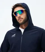 Chaqueta deportiva masculina de color azul marino, confeccionada en tejido técnico repelente al agua con acabado texturizado. Presenta cierre frontal con cremallera, capucha integrada y estampado de coordenadas en el pecho.