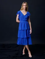 Vestido blanco de gasa con capas, marca Julia Jordan. Escote en V, manga corta con volados, corte en cintura y abertura central en espalda con cierre invisible.