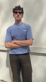 Remera celeste con estampado frontal en blanco, corte boxy y cuello redondo. Pantalón marrón de corte ancho y zapatillas deportivas blancas.