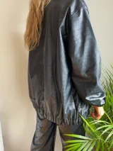 Campera negra de cuero sintético con textura crocco, cierre frontal con cremallera y cuello camisero.