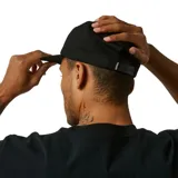 Gorro negro de cinco paneles con visera plana y parche bordado en el frente con diseño abstracto en blanco y negro.