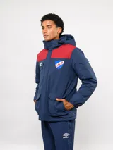 Parka de abrigo Umbro del Club Nacional de Football, con diseño de bloques de color en azul, rojo y blanco. Cuenta con capucha, cierre frontal, bolsillos frontales y el escudo del club bordado en el pecho.
