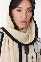 Bufanda de punto color marrón con capucha integrada y bordes en color crema. Presenta una etiqueta rectangular bordada con la palabra Anthea en uno de sus extremos.