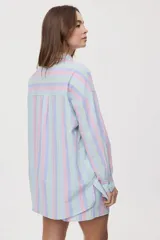 Camisa oversize de manga larga con estampado de rayas verticales en tonos rosado, celeste y verde menta. Cuenta con cuello camisero, cierre frontal con botones y un bolsillo aplicado en el pecho.