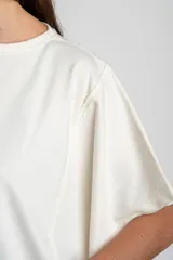 Remera oversize de algodón blanco crudo, con cuello redondo y mangas cortas anchas de corte relajado.