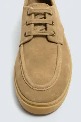 Zapato acordonado color beige, de piel con acabado serraje, con detalle de bordón en el empeine y suela a tono.