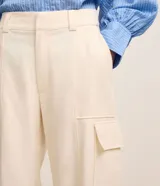 Pantalón wide leg de cintura alta en sarga de sastrería color marfil, con bolsillos cargo en los laterales y cierre frontal con botón y cremallera.
