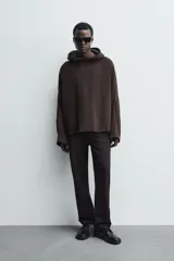 Sudadera de corte boxy fit en color marrón oscuro, con capucha, mangas largas y bandas laterales a contraste. Presenta un diseño de bajo con acabado irregular deshilachado.