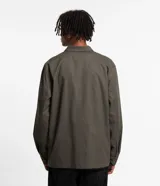 Campera masculina color verde oliva, estilo parka, confeccionada en sarga de algodón. Cuenta con cuello con solapa, cierre con botones, manga larga y múltiples bolsillos táticos delanteros.