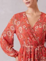 Vestido midi de gasa estampada con diseño floral, escote en V cruzado, cintura elastizada con lazo de ajuste y mangas largas con puños fruncidos. Incluye forro interno a tono.