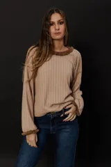 Buzo color nude de punto en lanilla con diseño de ochos y flecos en cuello y puños.