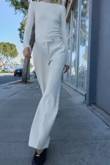 Pantalón blanco de tiro alto con pernera recta y pinzas marcadas en el frente. Cierre frontal con botón metálico dorado.