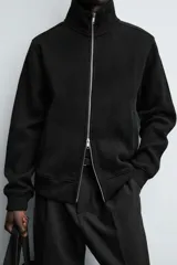Chaqueta regular fit de cuello subido, confeccionada en tejido técnico interlock de algodón con elasticidad. Presenta cierre frontal con cremallera, manga larga con puños en rib y bolsillos de vivo en la cadera.