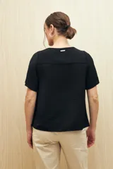 Blusa negra con textura, canesú con encaje, volados, corte fluido y mangas cortas amplias.