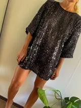 Minivestido negro cubierto de lentejuelas, de corte holgado y manga tres cuartos.