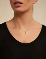 Charm de metal con baño de oro y cristal azul engastado en el centro, diseñado con una forma redonda y argolla superior para colgar.